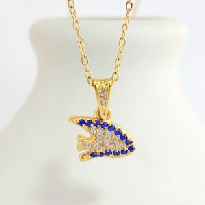Detailed close-up of a golden fish pendant with blue and white inlaid gemstones