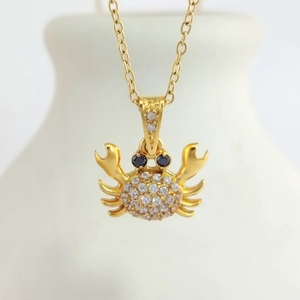 Macro shot of gold crab pendant necklace with sparkling cubic zirconia and blue stone eyes