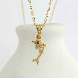 Macro shot of a gold dolphin pendant with sparkling white zircons on a fine O-chain