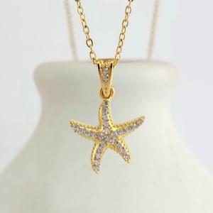 Macro shot of gold starfish pendant with cubic zirconia stones on stainless steel chain