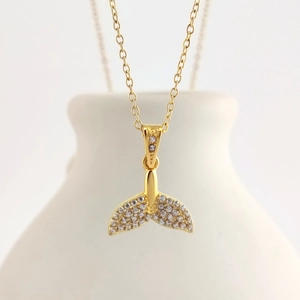 Close-up of a gold-plated fishtail pendant necklace with shimmering pavé crystal details