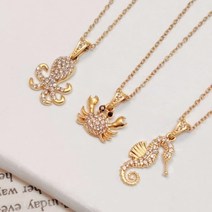Gold plated ocean jewelry set with octopus, crab and seahorse pendants on white board