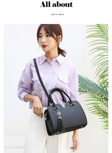 Detail of black faux crocodile skin handbag featuring silver V-logo and tassel charm