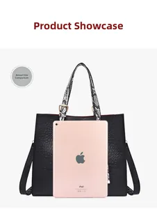 Black embossed leather tote bag showing large capacity with a tablet for scale