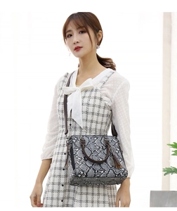 Detail of grey snake print tote bag with brown leather straps and tassel charm