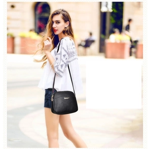 Close-up of black crossbody bag with lychee texture and golden zipper detail