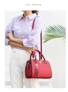 Detail of red crocodile texture handbag with gold V-hardware and tassel on a model