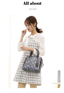 Detail view of grey snake print handbag with brown handles and metal chain tassel