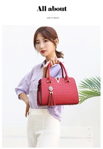 Detail of red crocodile texture handbag with silver V-hardware and stylish tassel