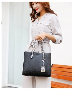 Detail of black embossed tote bag with snakeskin print straps and gold hardware