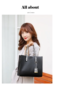 Detail of black crocodile texture handbag with snake pattern handles and metal hardware