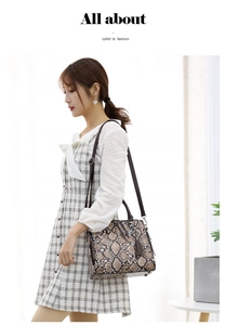 Brown snake pattern handbag with metal tassel shown as a shoulder bag on a model