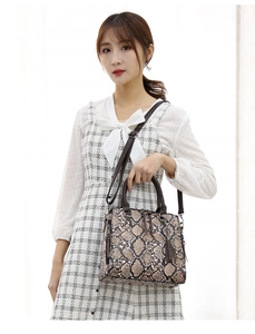 Detail of faux snake skin handbag showing side metal zipper and long tassel decoration