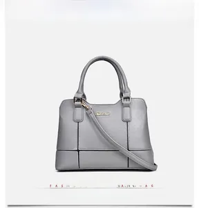 Close-up of grey leather handbag with grid stitching and golden metallic logo detail