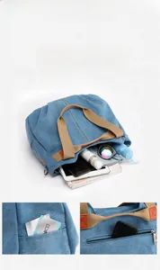 Detail view of large capacity blue canvas tote bag with brown handles and side pockets