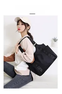 Close-up of a black oxford tote bag with functional side pocket and wide strap details