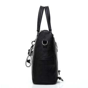 Black PU leather handbag with side pocket and checkered bear charm on white background