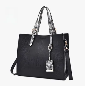 Detailed macro view of black crocodile embossed tote with snakeskin textured handles