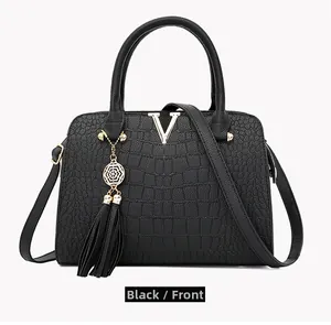 Close-up of black faux crocodile embossed bag featuring gold V-logo and tassel charm