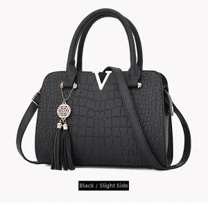 Detailed side view of black faux crocodile leather handbag with gold V logo and tassel