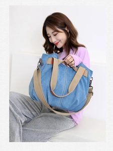 Detailed view of blue canvas tote bag with khaki webbing straps and contrast stitching