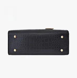 Detail view of the black crocodile pattern bag bottom with four gold protective metal feet