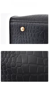 Close-up of black crocodile embossed leather handbag with golden metal bottom studs