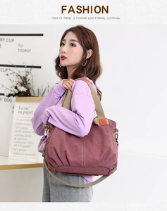 Detail view of burgundy canvas handbag with thick straps and adjustable shoulder strap