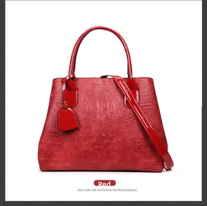 Detail of red crocodile pattern embossed leather tote bag with handles and strap