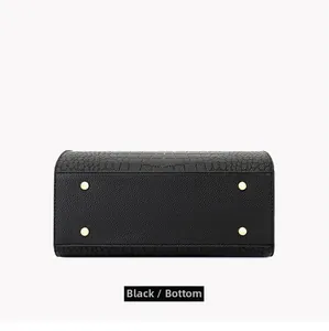 Detail of black pebbled leather handbag bottom with four protective gold metal feet