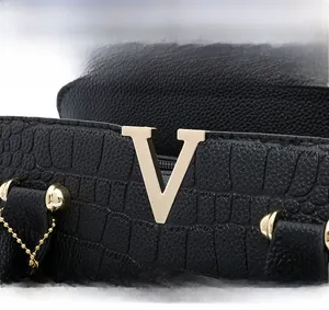 Macro shot of black crocodile embossed leather handbag with golden V-shaped metal hardware