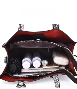 Spacious interior of snake-patterned handbag with red lining showing storage capacity