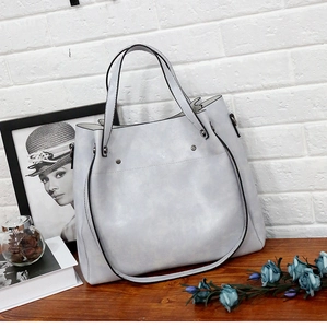 Detalle de bolso de mano de cuero PU gris con tachuelas metálicas y correa ajustable