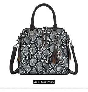 Detail view of snakeskin pattern handbag with cat pendant and fringe tassel accessories