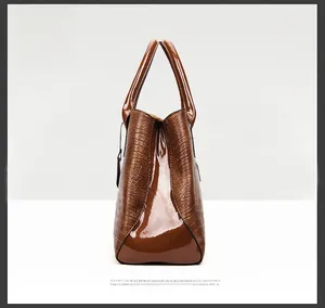 Close-up of brown crocodile pattern leather handbag with glossy patent leather stitching details