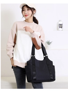 Woman in casual sweatshirt carrying a large black nylon tote bag for daily commute