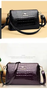 Detail of crocodile-embossed leather texture and golden kangaroo logo on crossbody bag
