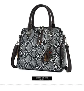 Detail view of crocodile pattern handbag with snake skin texture and metal cat charm
