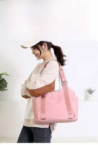 Pale pink oxford fabric tote bag shown on a model with adjustable strap and side pocket