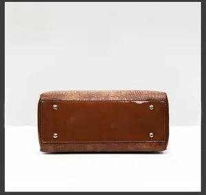 Detail view of the dark brown crocodile pattern handbag base with gold metal feet