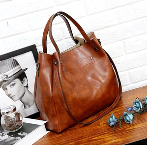 Primer plano de un bolso tote de cuero marrón caramelo sobre una mesa de madera y fondo