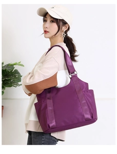 Detail of deep purple oxford tote bag with wide strap worn by a model in interior setting