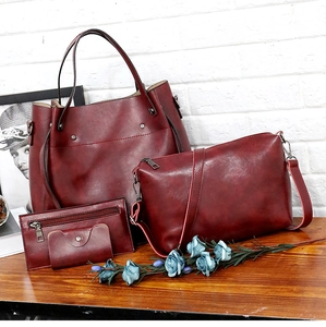 Juego de cuatro bolsos burdeos vintage de cuero PU encerado sobre una mesa de madera