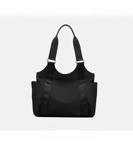 Front view of black nylon tote bag with wide straps and silver metal hardware details