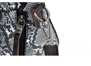 Macro detail of silver metal hook and brown leather connector on snakeskin pattern handbag