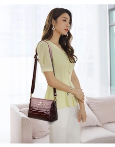 Detailed view of wine red patent leather shoulder bag with crocodile pattern and kangaroo logo