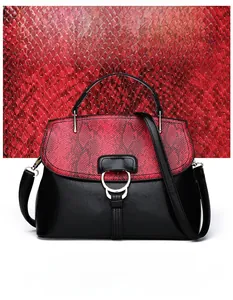 Détail du rabat motif serpent rouge et boucle métallique sur sac en cuir noir brillant