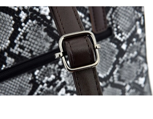 Detailed close-up of brown leather strap with silver buckle on snakeskin handbag