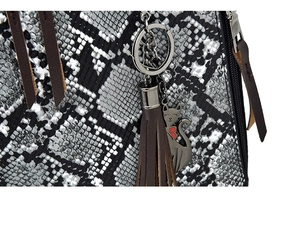 Detailed view of snakeskin pattern leather bag with a cute cat pendant and brown tassel