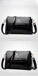 Detail of black crocodile pattern patent leather handbag with golden kangaroo logo